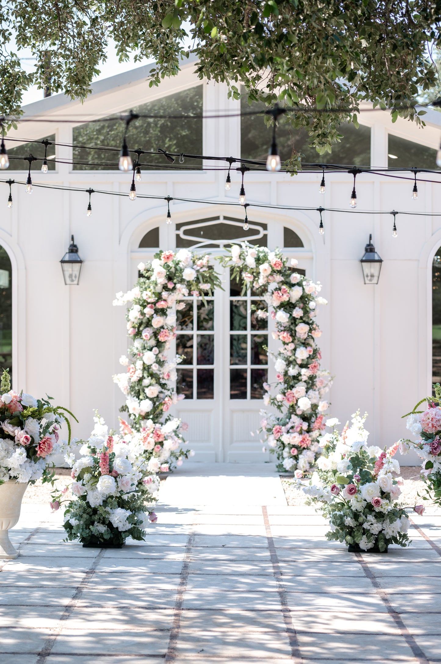 pink and white wedding setup with arch, aisle meadows and urns in outdoor garden setting