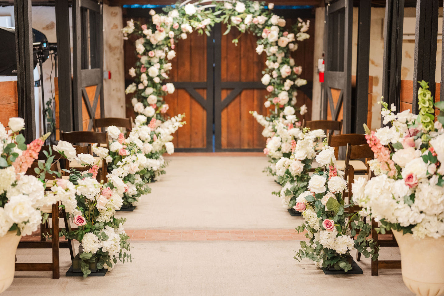 Lush pink and white Blushing Bride arch and aisle flowers in indoor ceremny setting