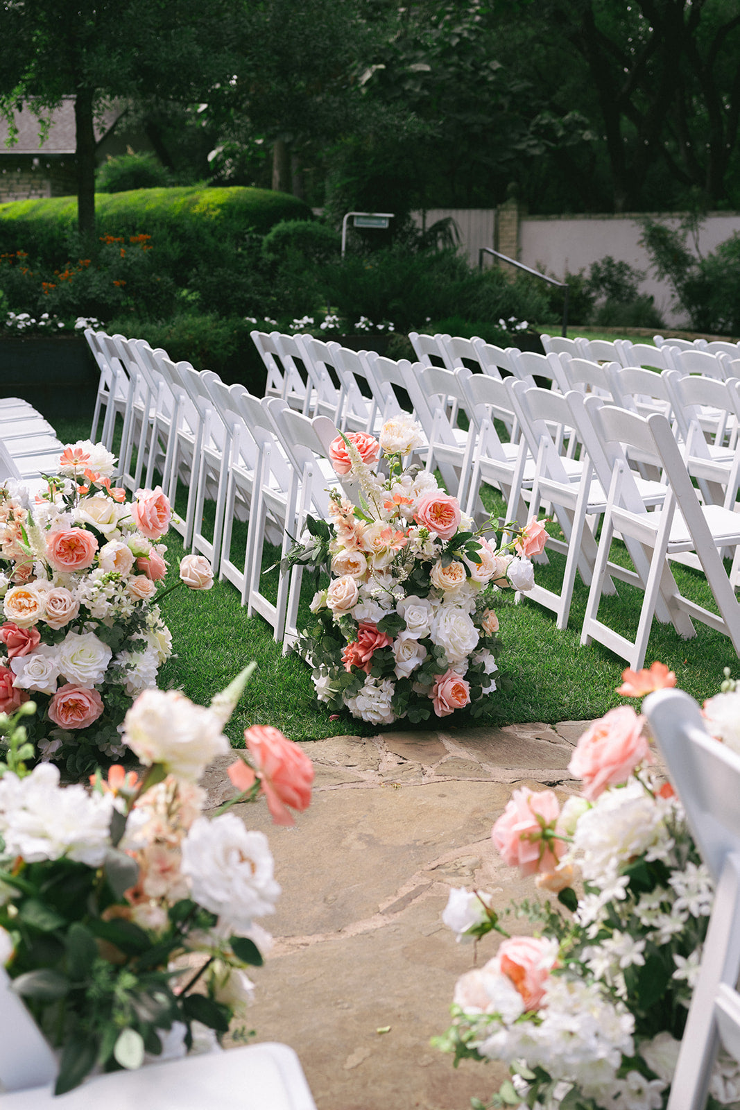 Decorative floral arrangements on white chairs at an outdoor event.