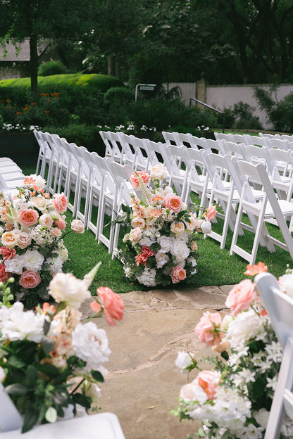 Decorative floral arrangements on white chairs at an outdoor event.