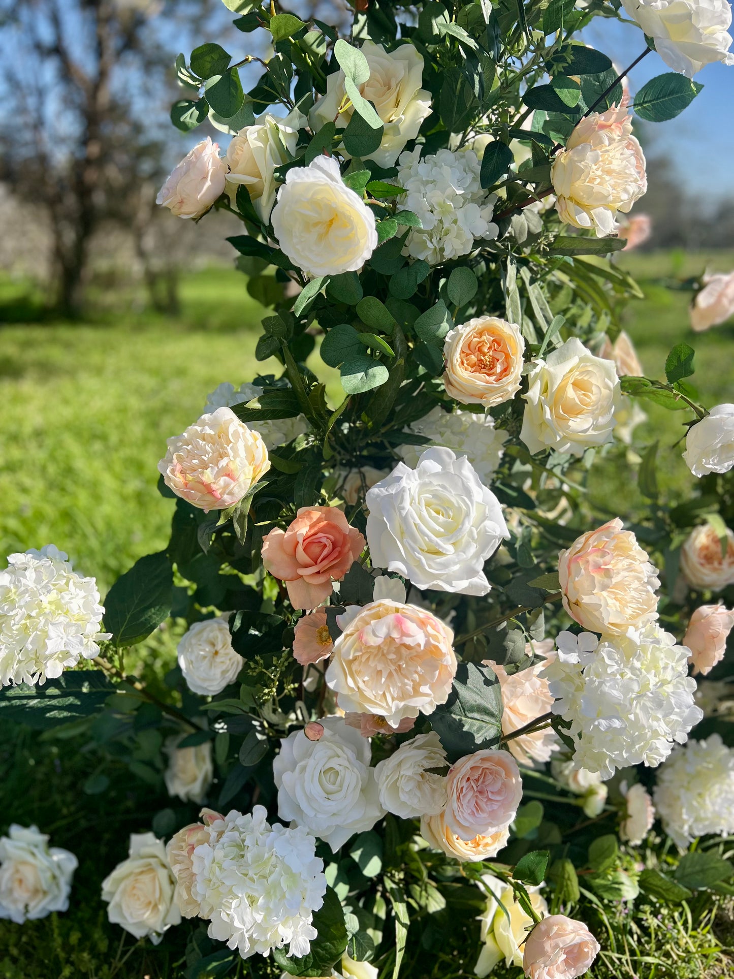 close up of whitem peach and yellow garden flowers on floral arch 