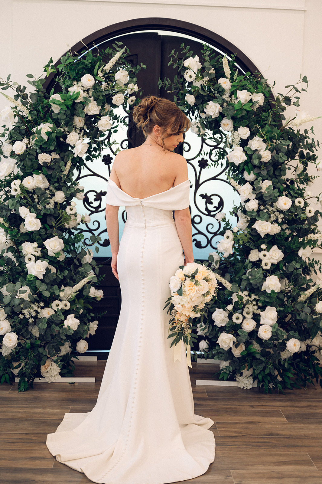 Bride in front of the Green and white floral arch