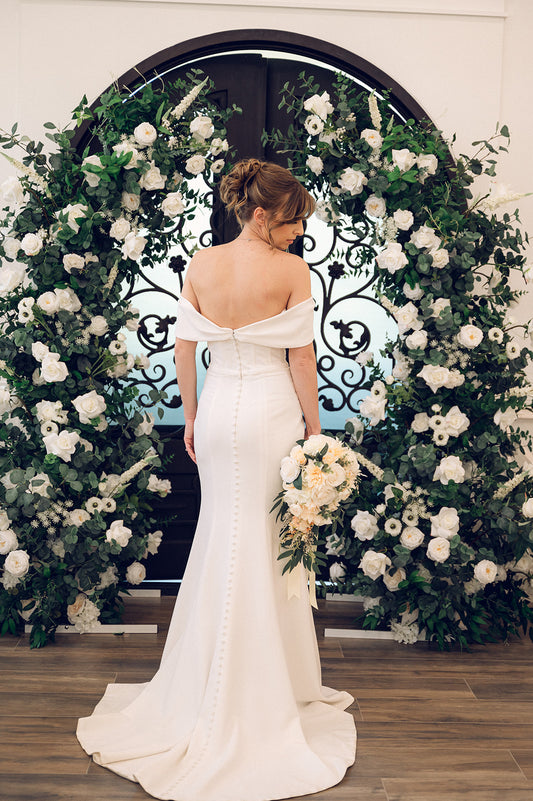 Bride in front of the Green and white floral arch